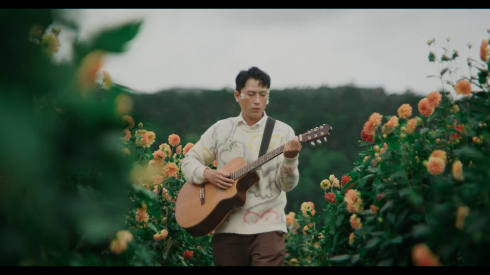 A guitarist surrounded by flowers and greenery, graded with Deep Green