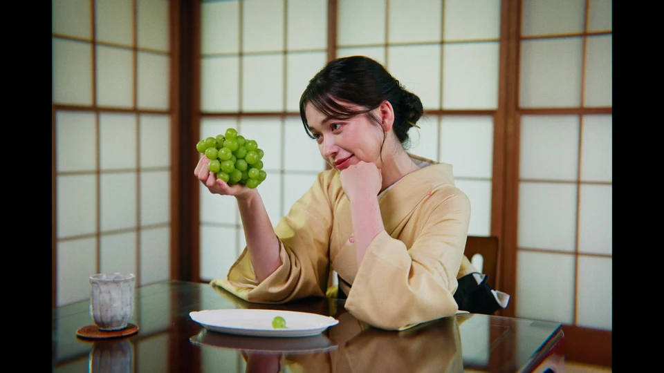 A woman holding green grapes indoors, graded with Everyday Film