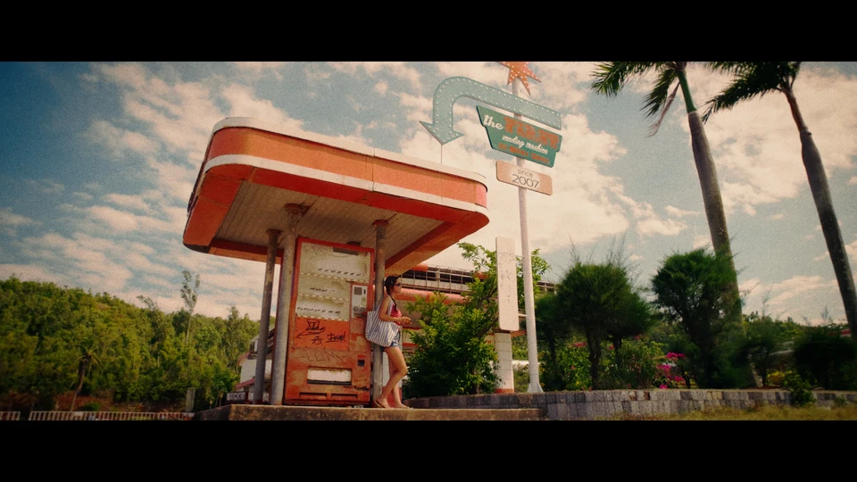 A roadside building and palms under a blue sky, graded with Golden Hour